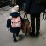 Copil care ține în mână un pașaport și un bilet de avion, în sala de așteptare a unui aeroport