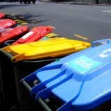 Containere colorate pentru colectarea separată a deșeurilor, aliniate pe o stradă dintr-un cartier