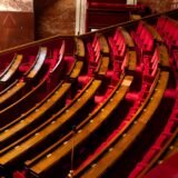 Persoană care redactează o scrisoare oficială la un birou, cu documente și un pix alături