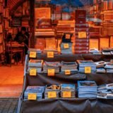 Proprietar de magazin mic care scrie etichete de preț pentru produsele aranjate pe tejghea