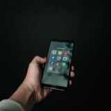 Mână care ține un telefon mobil cu o notificare nouă pe ecran, într-o cameră slab luminată