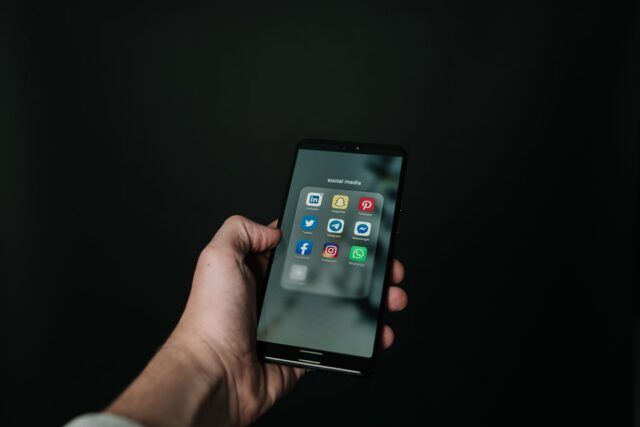Mână care ține un telefon mobil cu o notificare nouă pe ecran, într-o cameră slab luminată